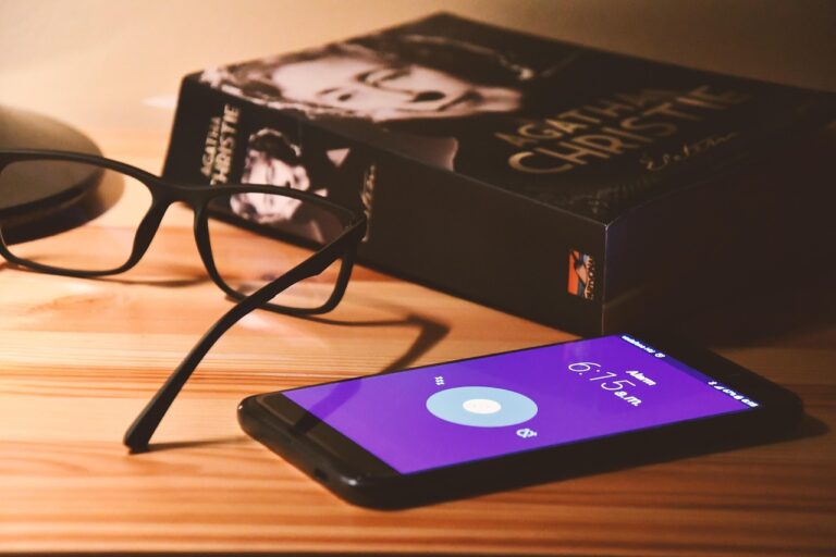 Immagine di un cellulare posato su un comodino accanto a un letto, simbolo dei rischi di dormire vicino al dispositivo.